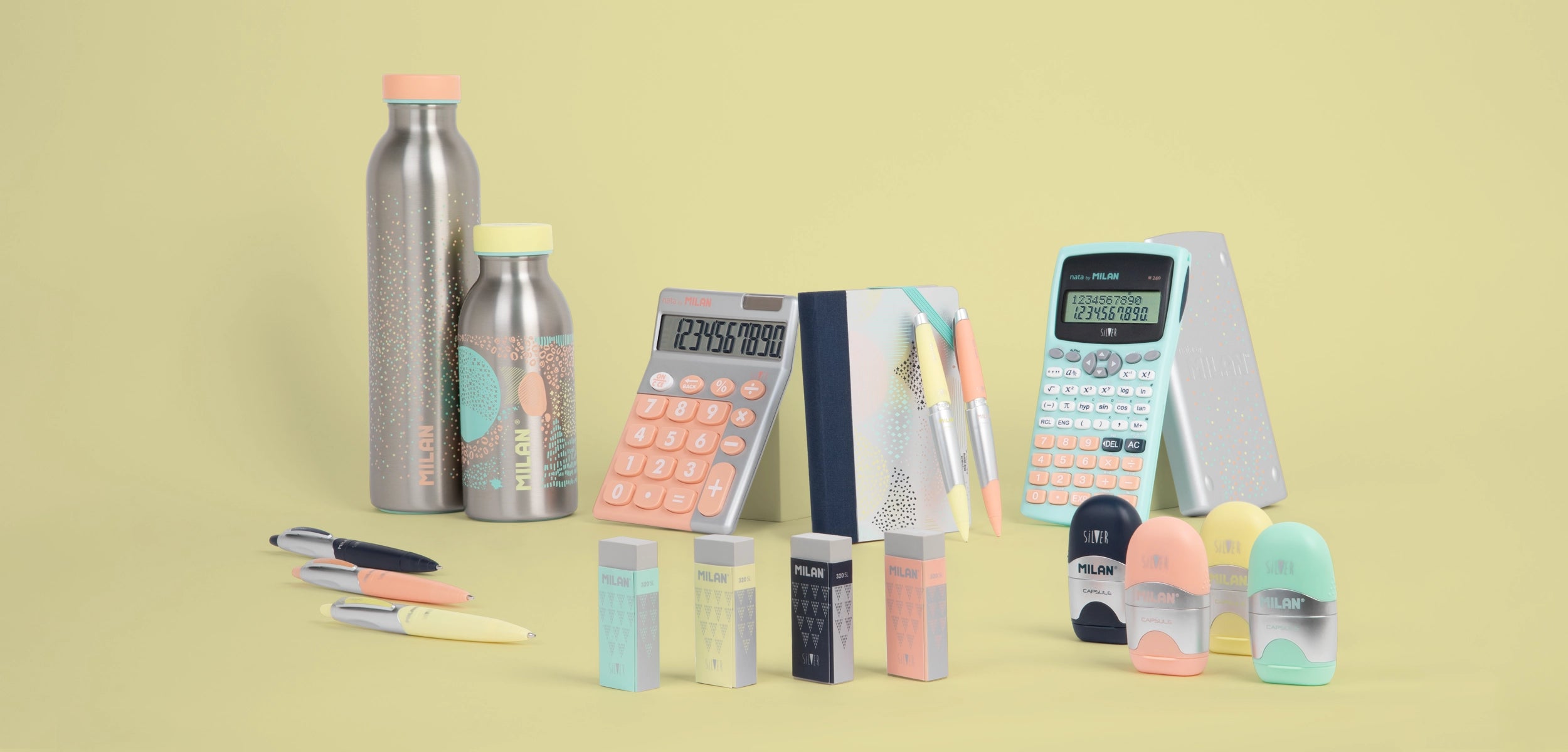 Bodegón de la colección Silver de MILAN que muestra una variedad de productos, incluyendo botellas isotérmicas, una libreta, una calculadora científica, afilaborras y bolígrafos